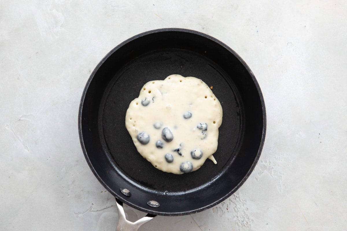 Pancake batter in a skillet before flipping.