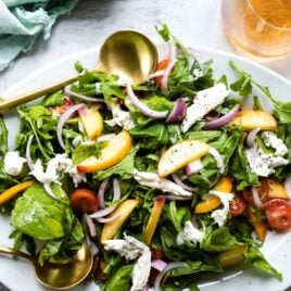 A platter of burrata salad with peaches.
