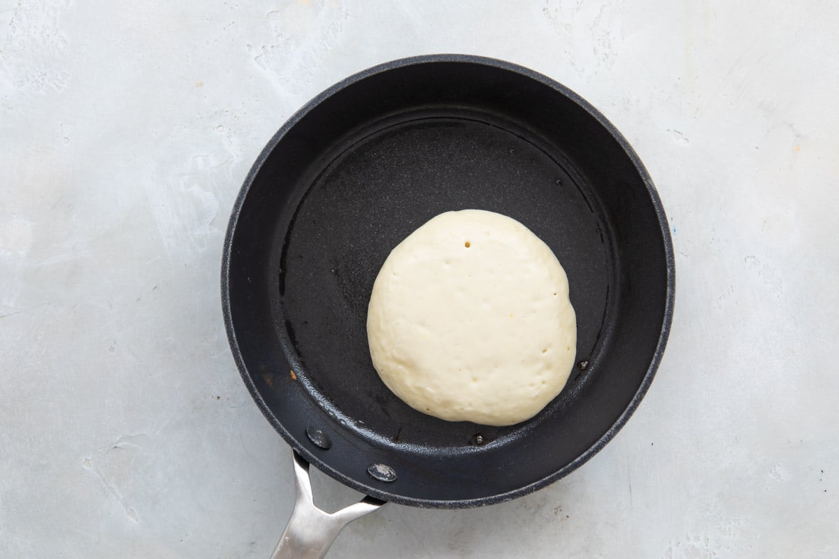 Pancake batter in a skillet before flipping.
