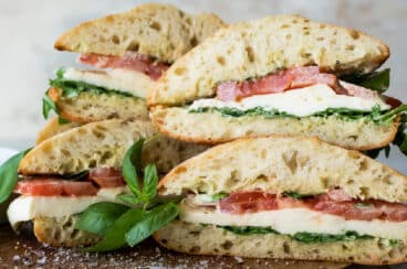 A stack of Caprese Sandwiches on a wooden cutting board.