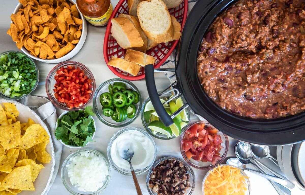 A crockpot full of chili with toppings on a Chili Bar.