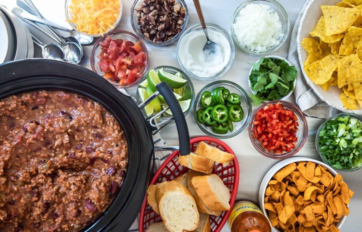 A crockpot full of chili with toppings on a Chili Bar.