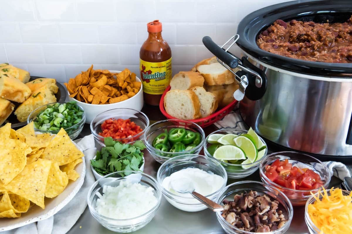 A crockpot full of chili with toppings on a Chili Bar.