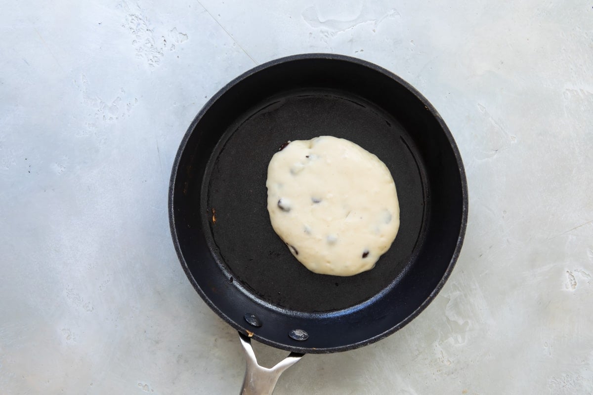 Pancake batter in a skillet before flipping.
