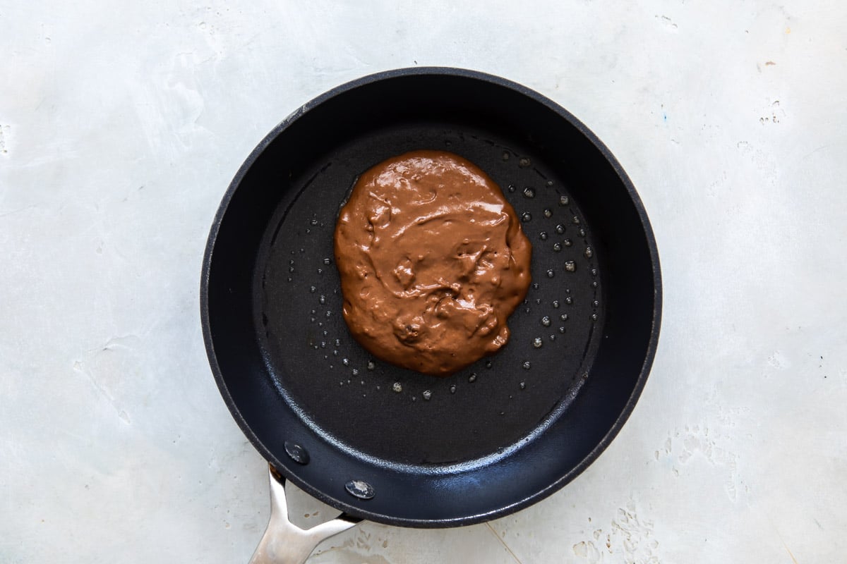 Pancake batter in a skillet before flipping.
