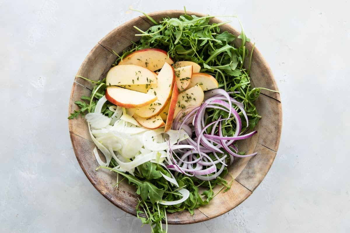 A wooden bowl full of fennel salad with apples.