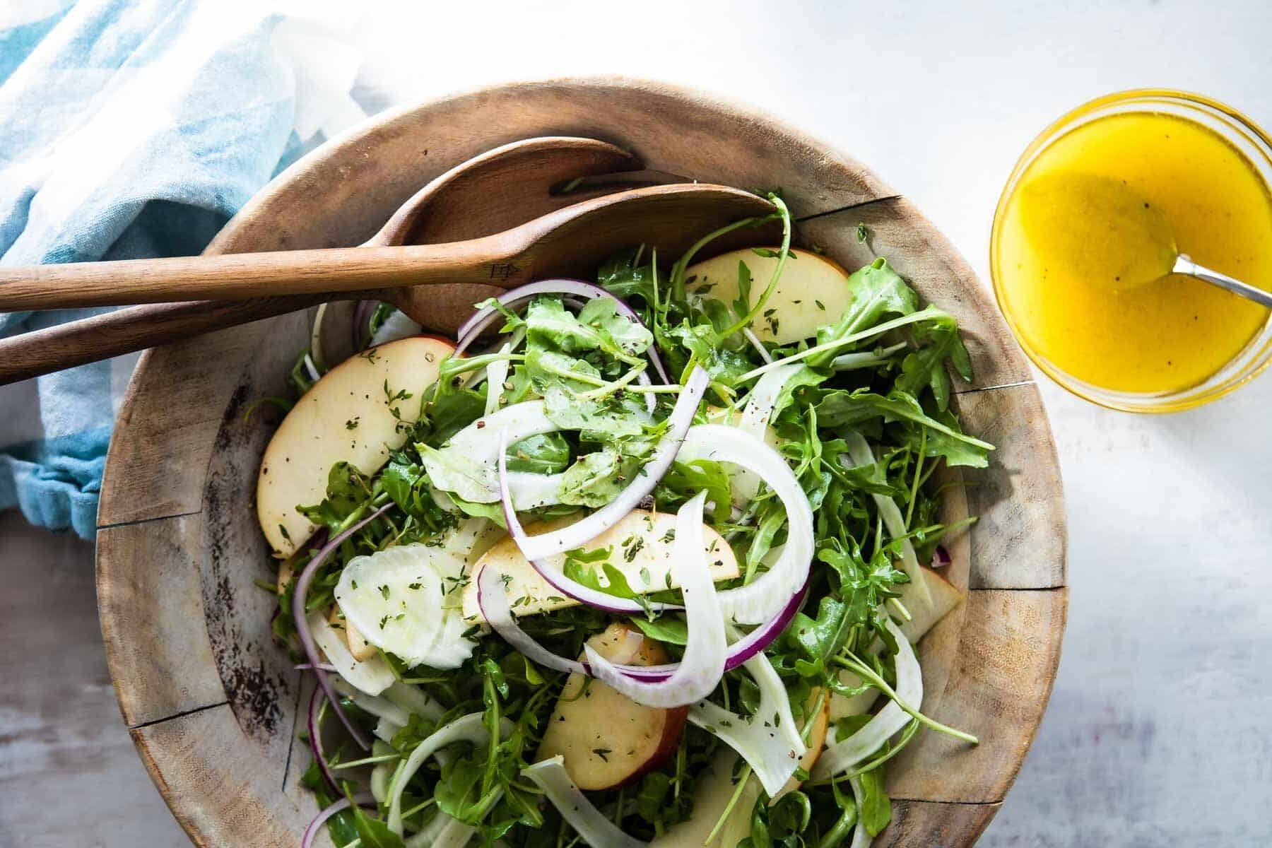 A wooden bowl full of fennel salad with apples.