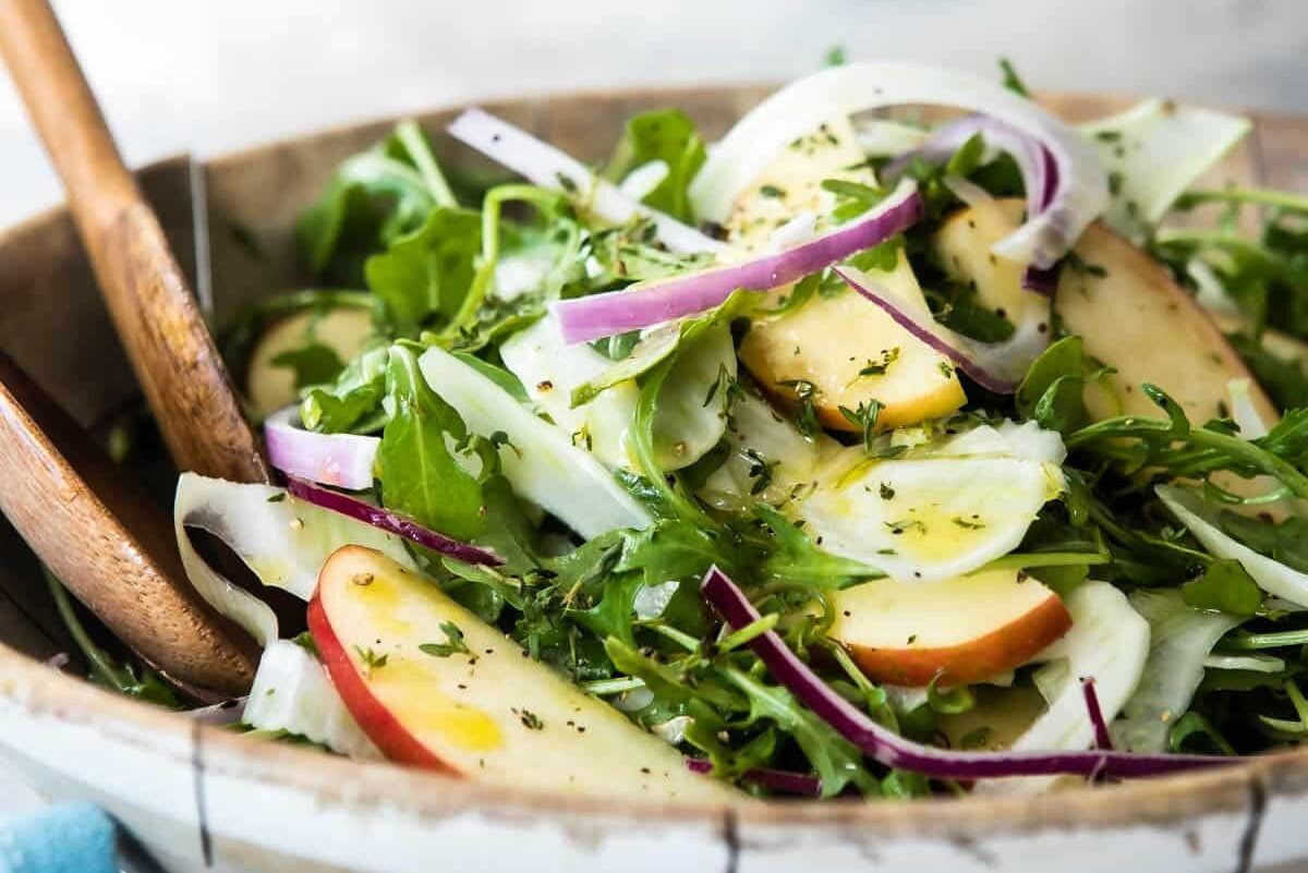 A wooden bowl full of fennel salad with apples.