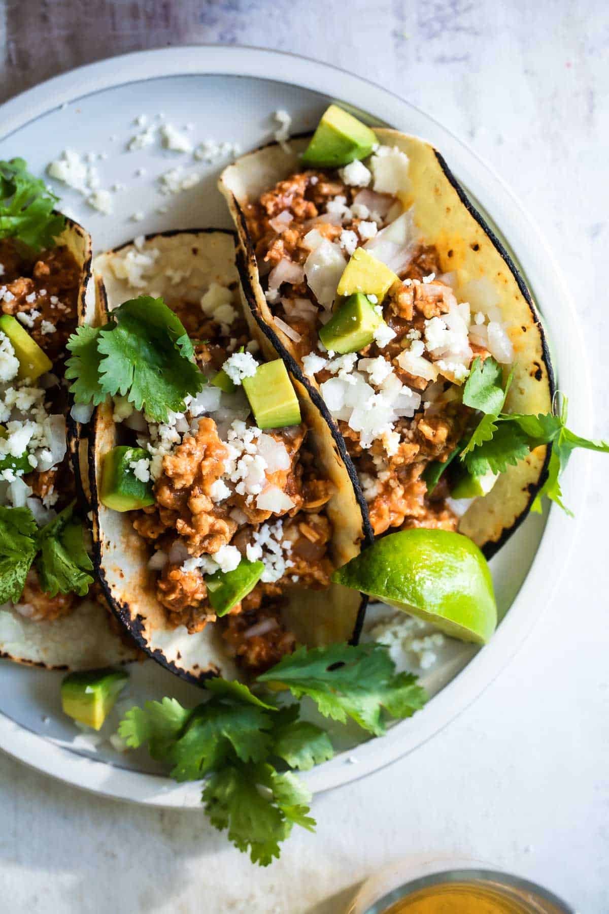 A platter of ground chicken tacos with cilantro and onions.