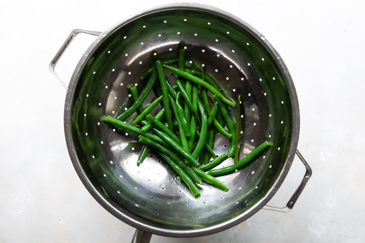 Blanched green beans in a colander.