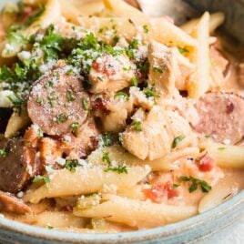 One pot cajun pasta in a blue bowl with a silver fork.