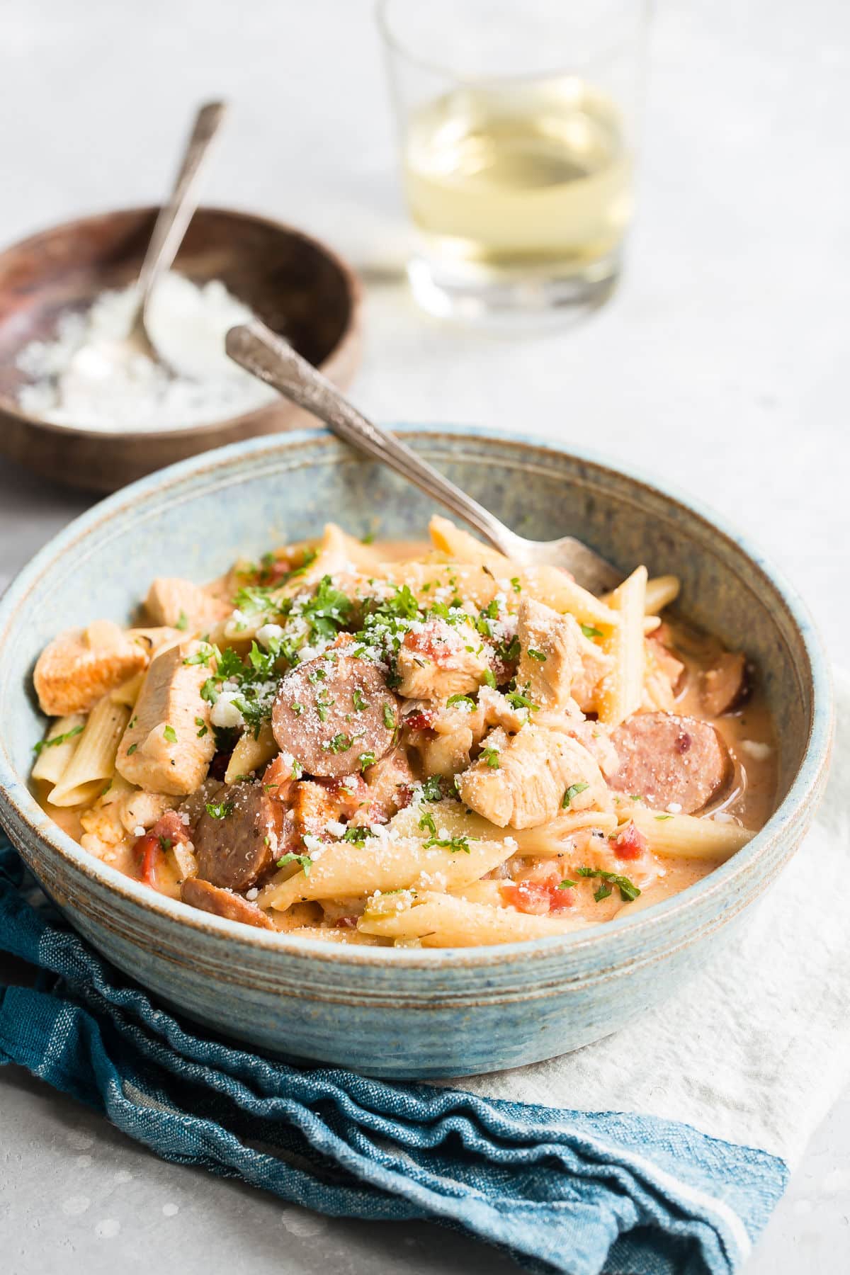 One pot cajun pasta in a blue bowl with a silver fork.