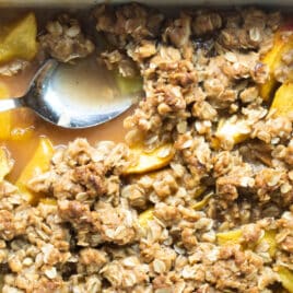 Peach Crisp in a baking dish with a spoon.