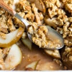 Pear crisp in a baking dish with a spoon resting in it.