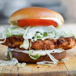 A pork tenderloin sandwich on a wooden cutting board.
