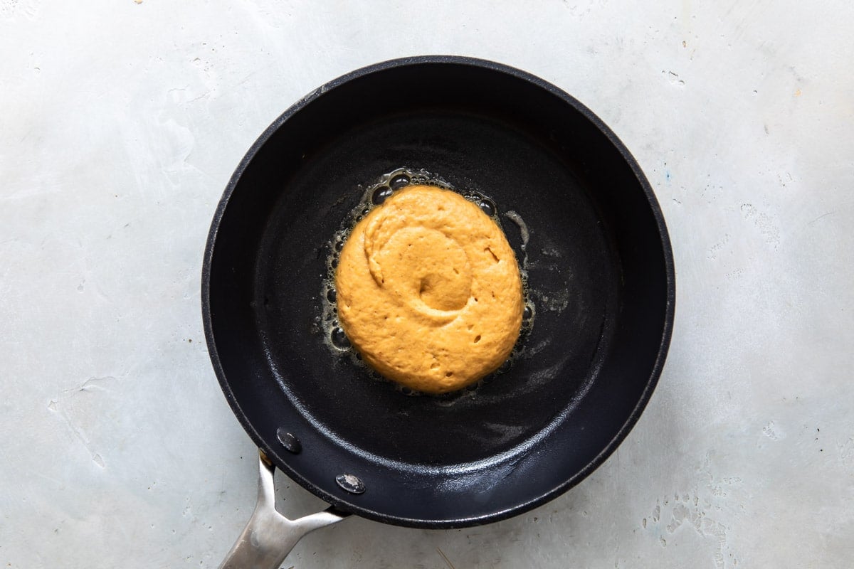 Pancake batter in a skillet before flipping.