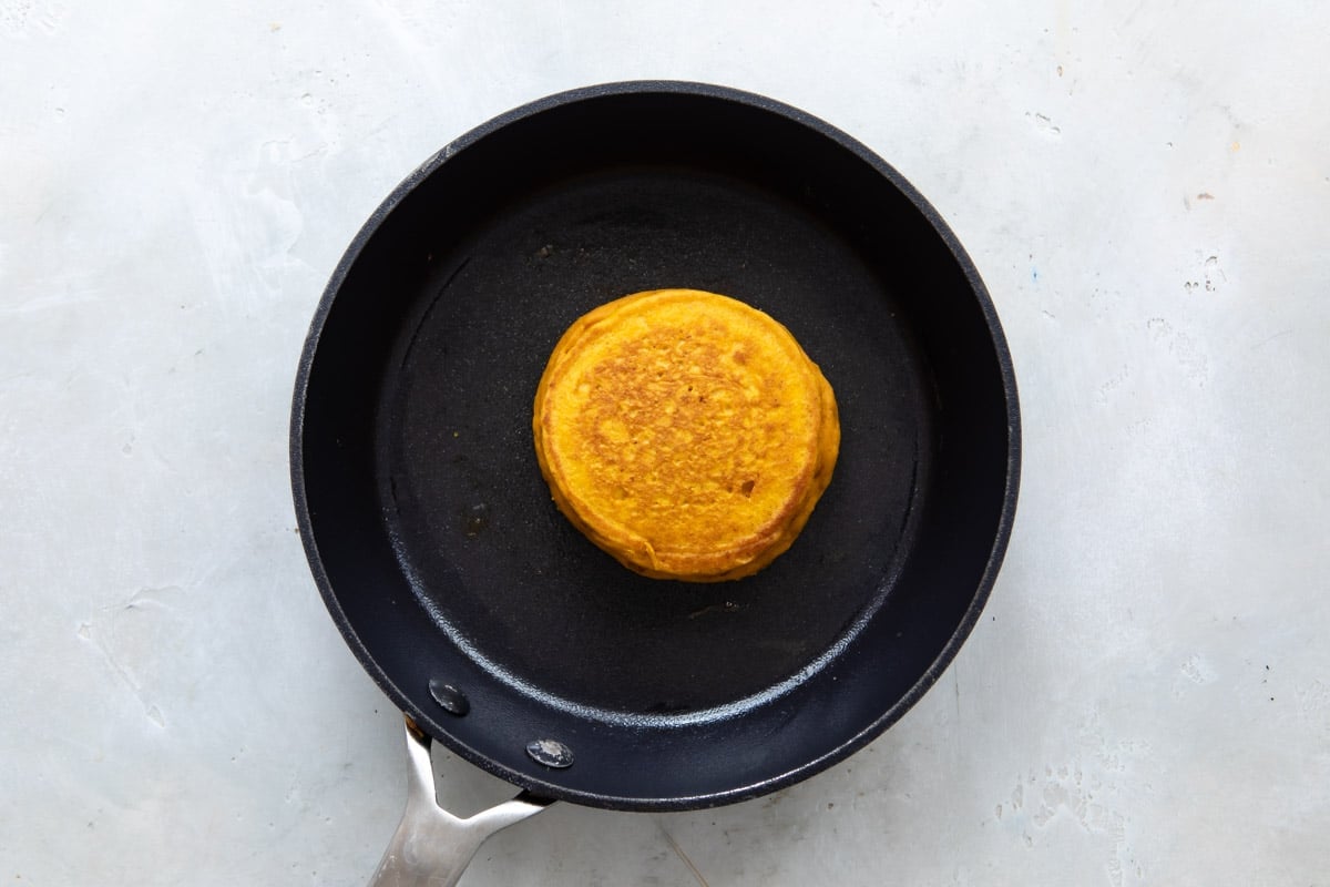 A Pancake in a skillet after flipping so cooked side is up.