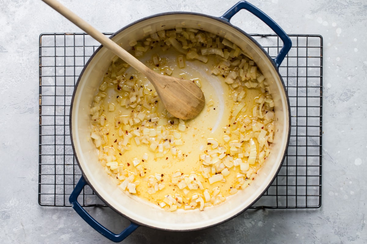 Onion being cooked in oil in a Dutch oven.