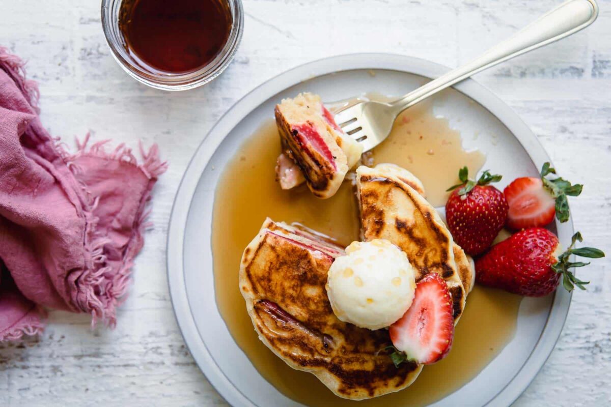 A stack of strawberry pancakes on a plate.
