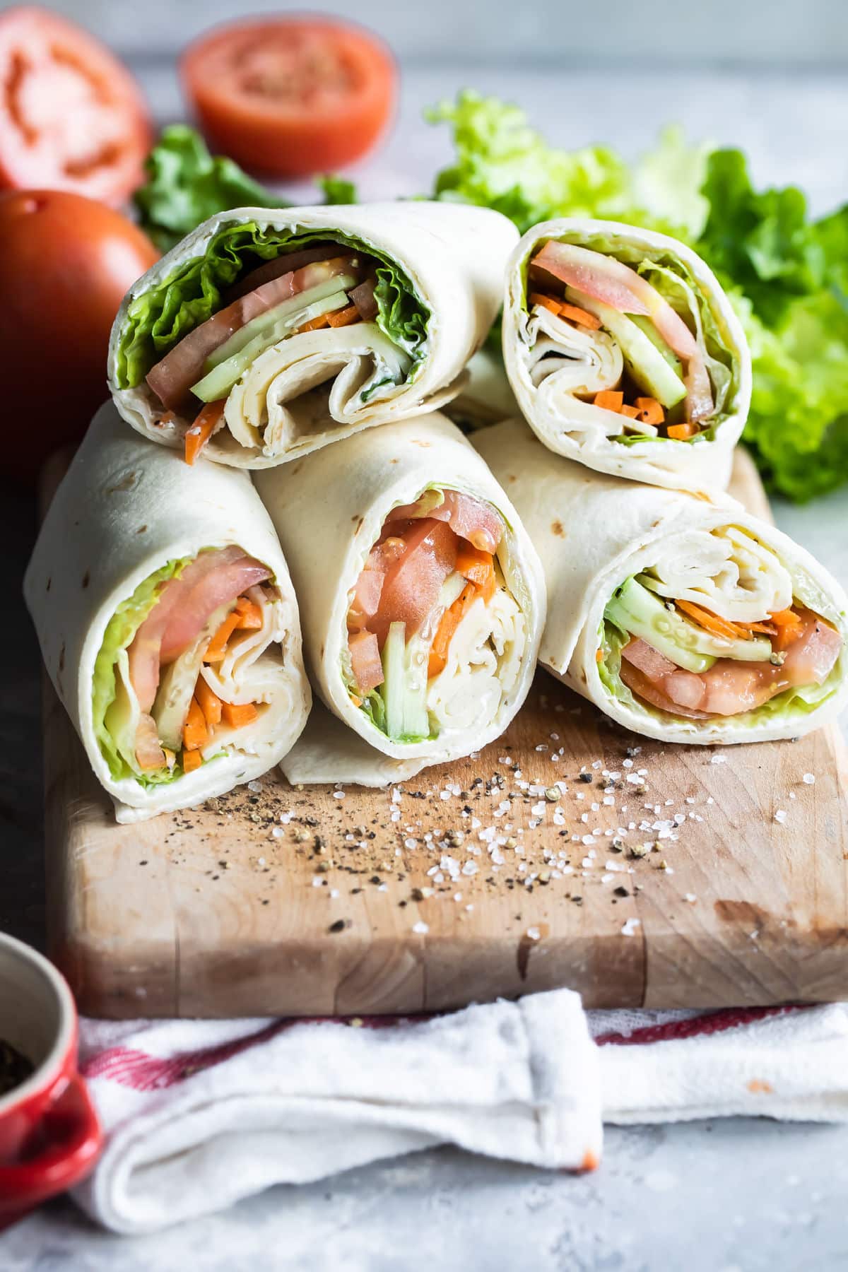 A pile of veggie wraps cut open on a cutting board.