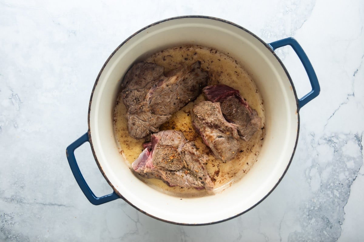 Chunks of beef roast cooking in dutch oven.