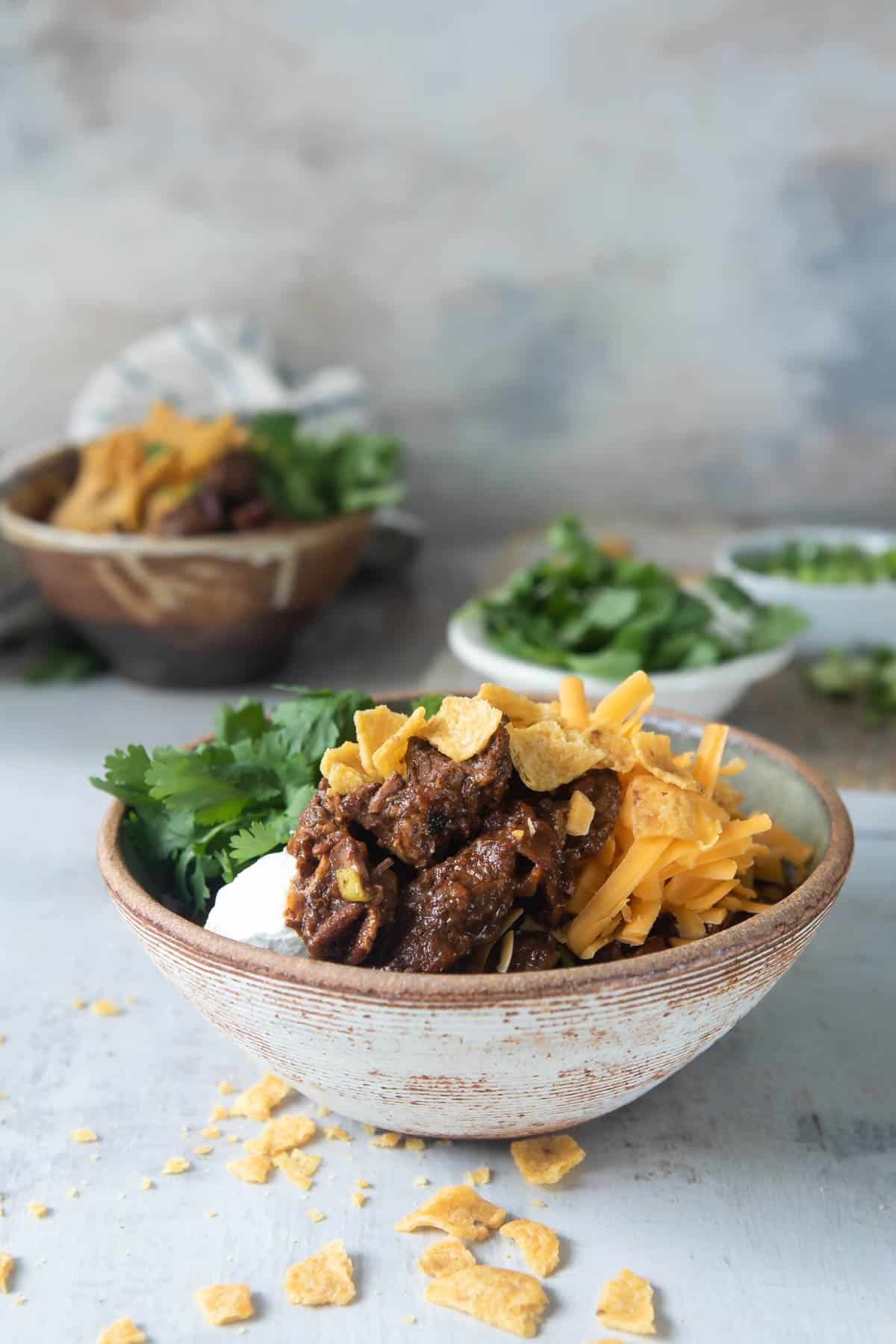 Two bowls of chili con carne with all the toppings.