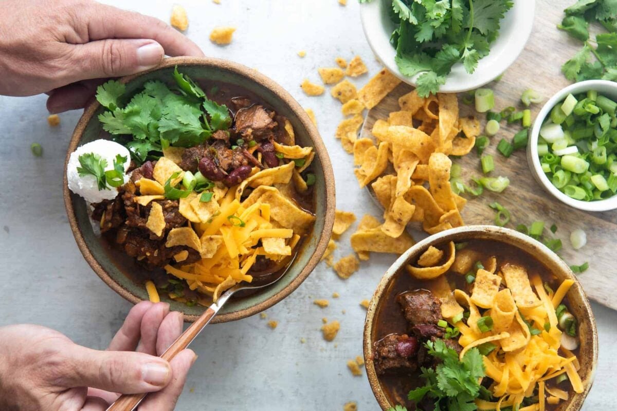 Two bowls of chili con carne with all the toppings.