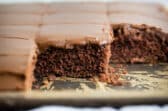 A pan of Texas sheet cake cut into squares and some squares removed from the pan.