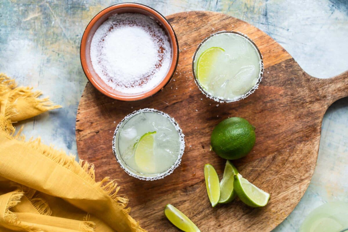 A wooden board with 2 Virgin margaritas on it.