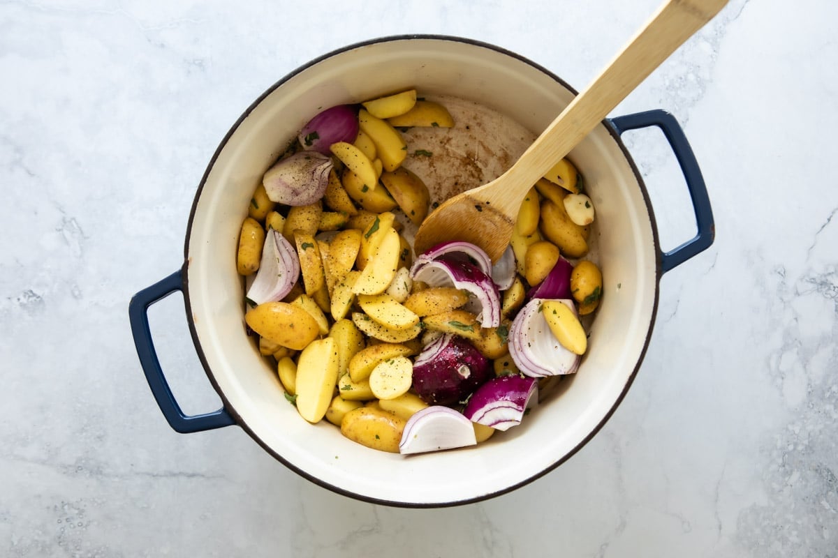 Vegetables and a wooden spoon in a Dutch oven.