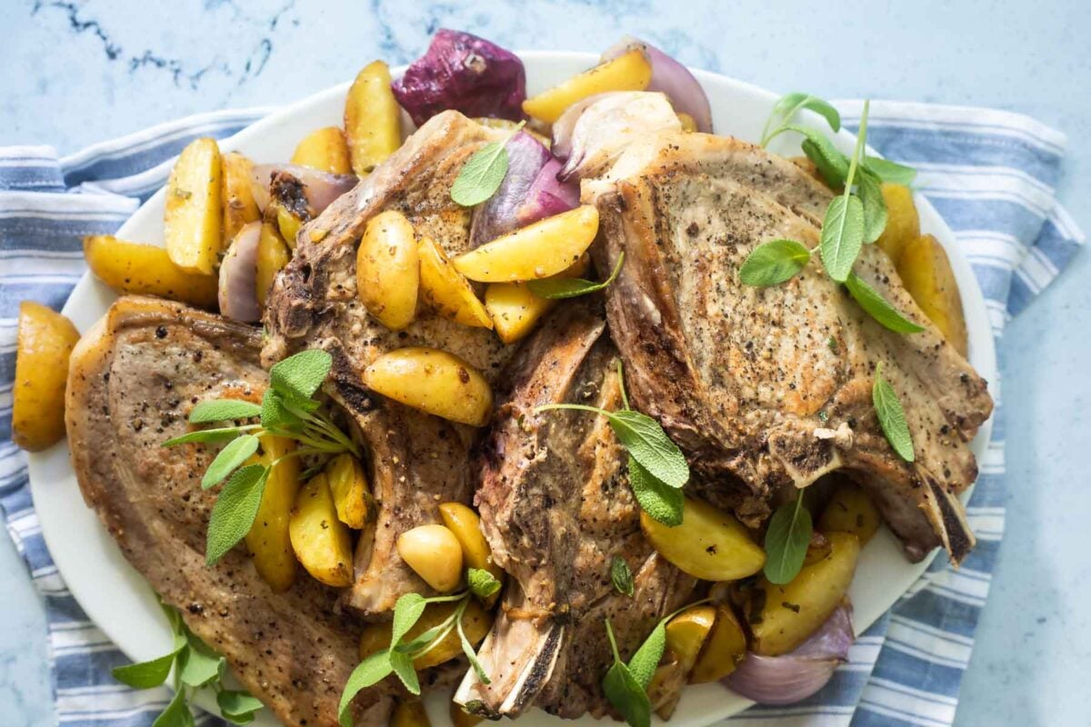 Baked pork chops on a platter with vegetables.