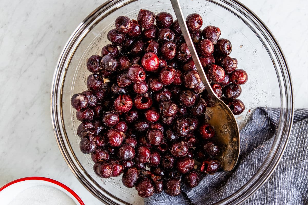 Cherries mixed with sugar in a bowl.