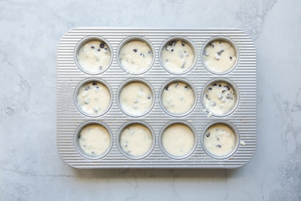 Chocolate chip muffin batter in a muffin tin.
