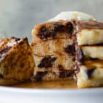 A stack of four chocolate chip pancakes on a plate.