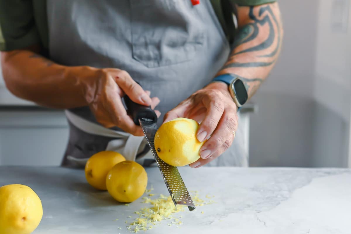 A lemon being zested with a microplane grater.