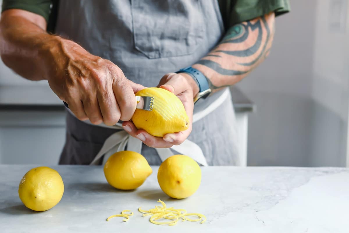 A lemon being zested with a zester.
