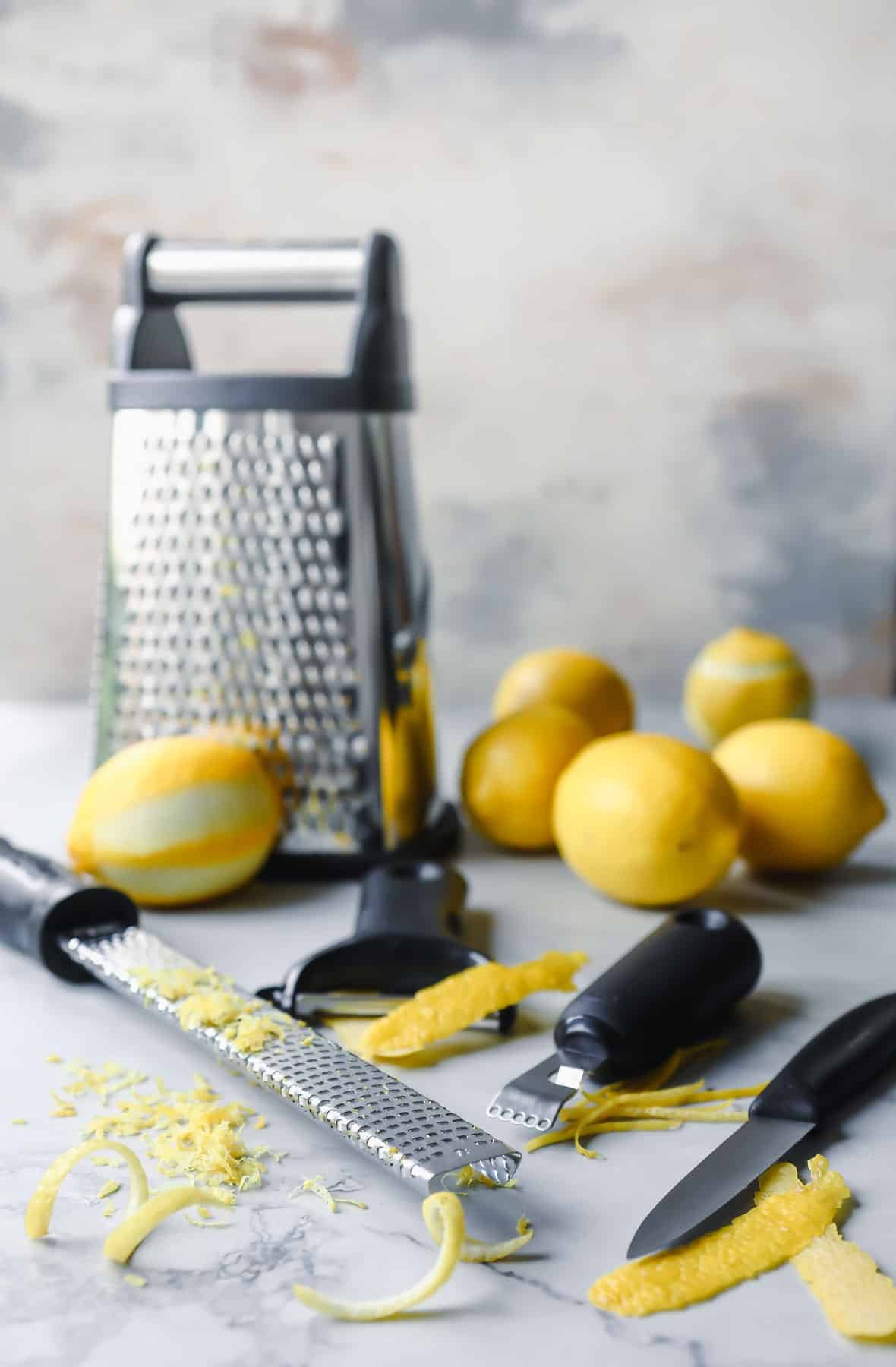 Zested lemons and tools to zest a lemon on a countertop.