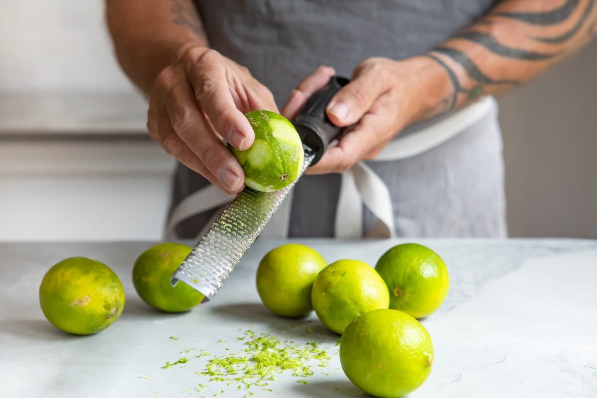Someone using a microplane grater to zest a lime.