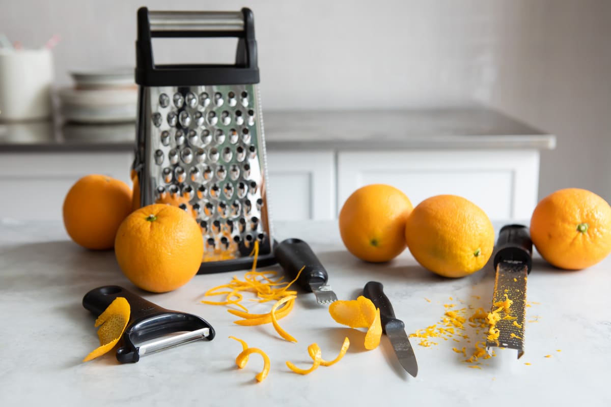 Five oranges on a countertop that have been zested.