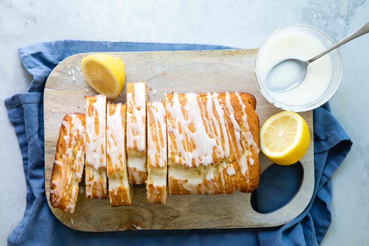 A sliced lemon yogurt cake on a wooden cutting board.