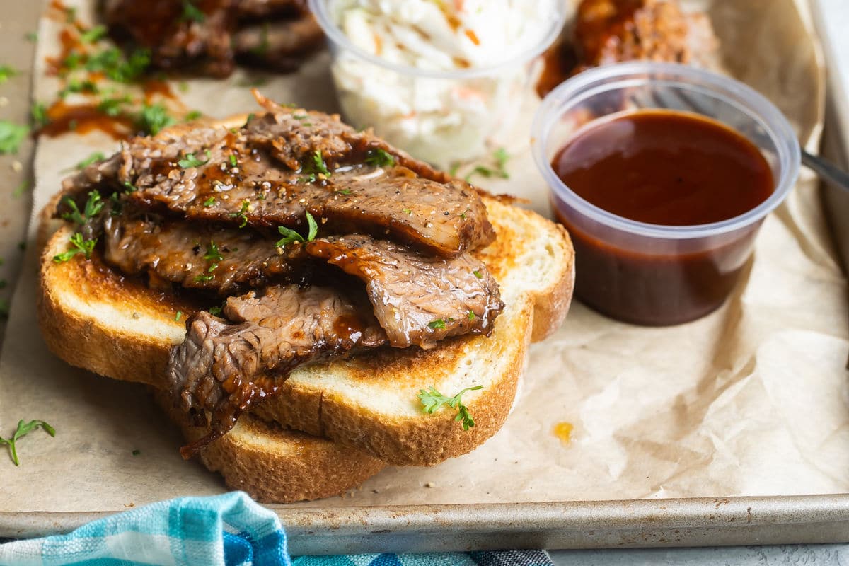 Slow cooker beef brisket slices on toast on a metal serving platter.