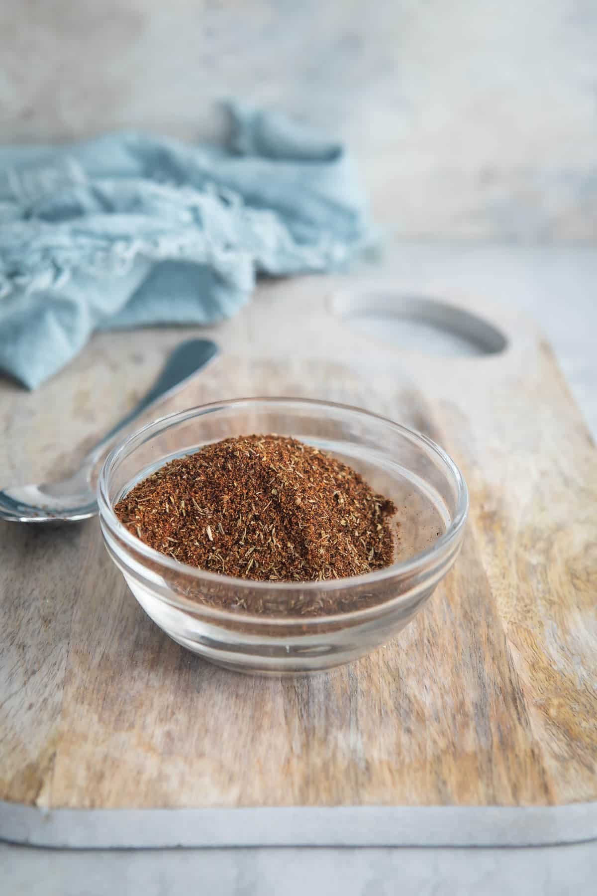 A bowl of homemade chili seasoning on a cutting board.