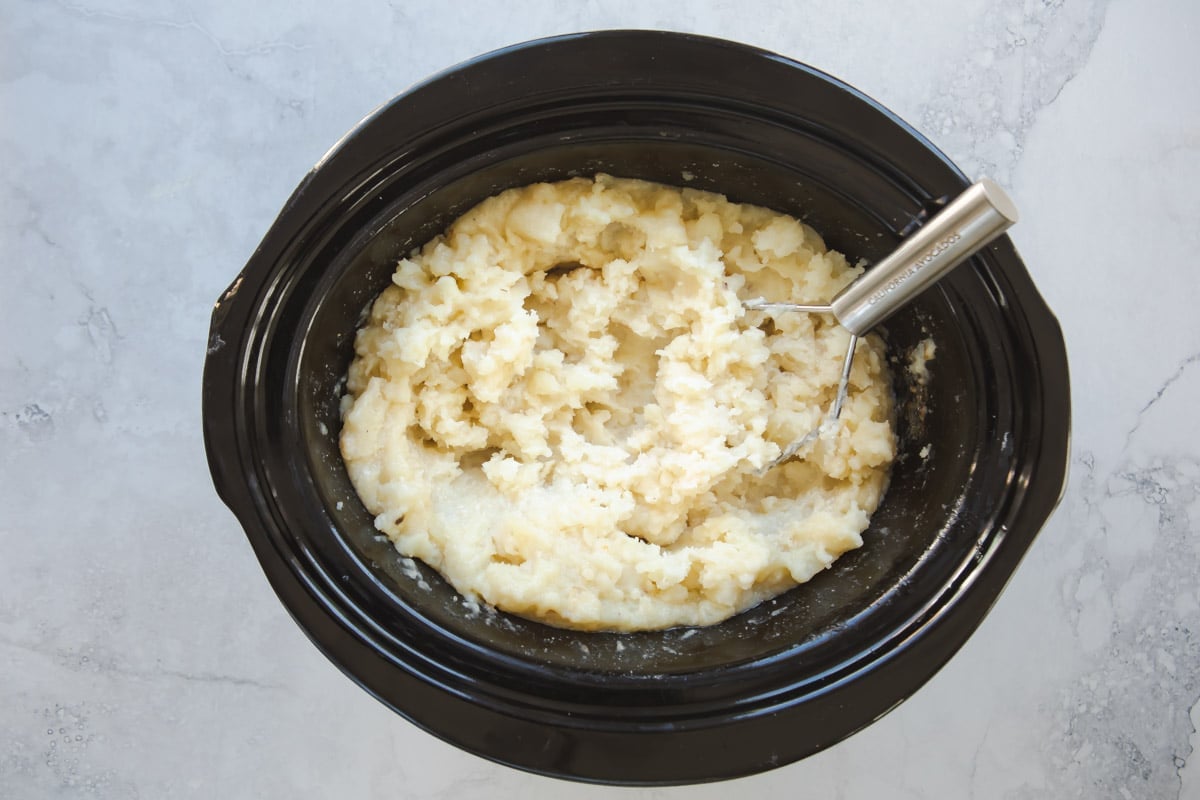 A crockpot full of mashed potatoes.