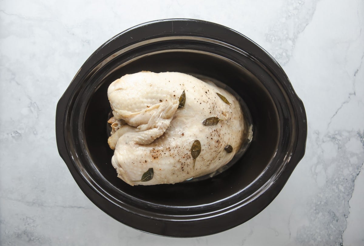 A cooked turkey breast in a crockpot.