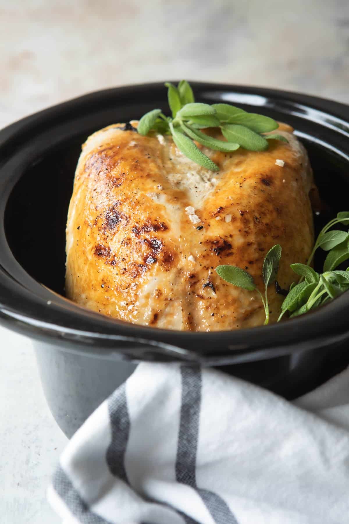 A cooked turkey breast in a crockpot.