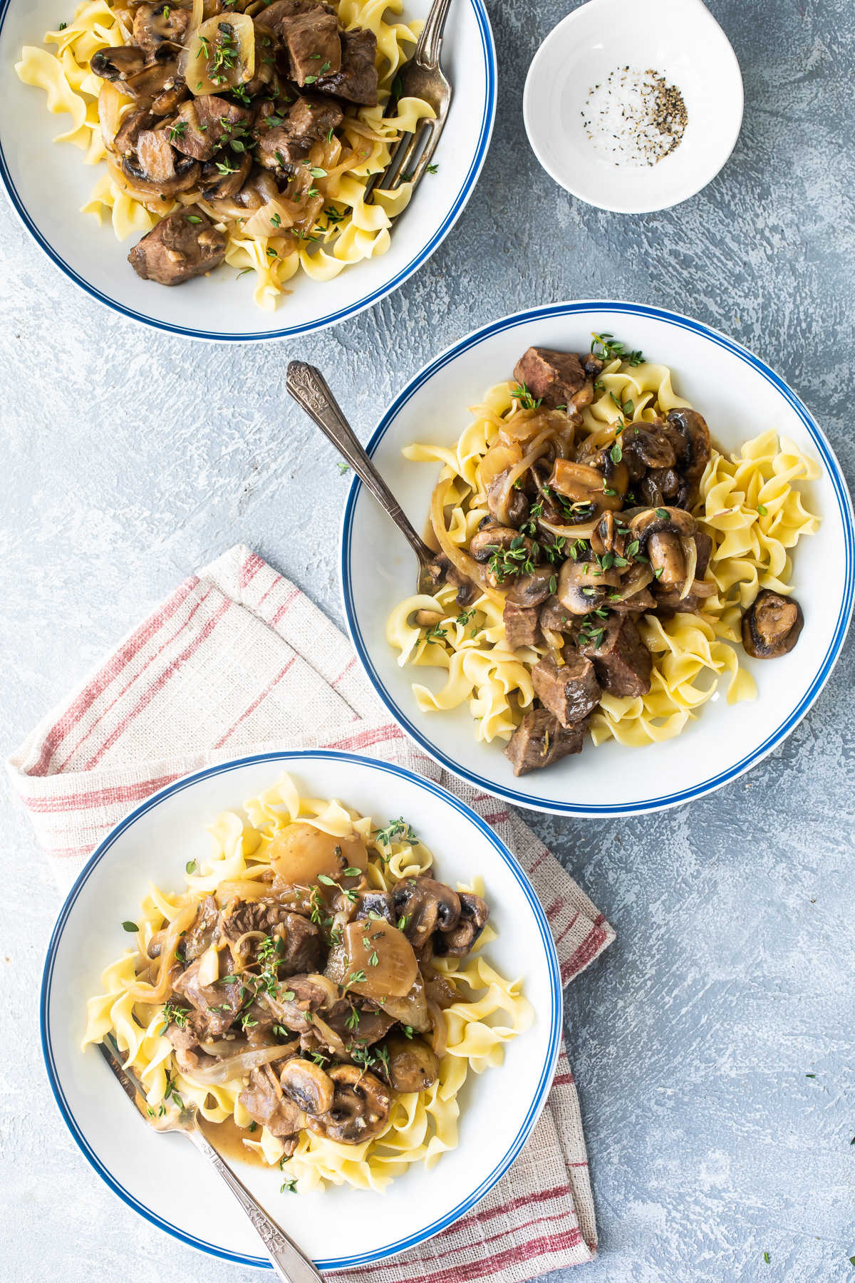 Three bowlls of steak tips with mushroom gravy in white bowls.