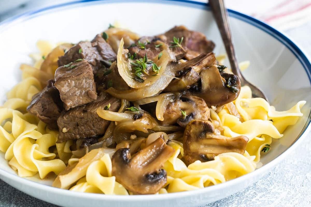 Steak tips with mushroom gravy in a white bowl.
