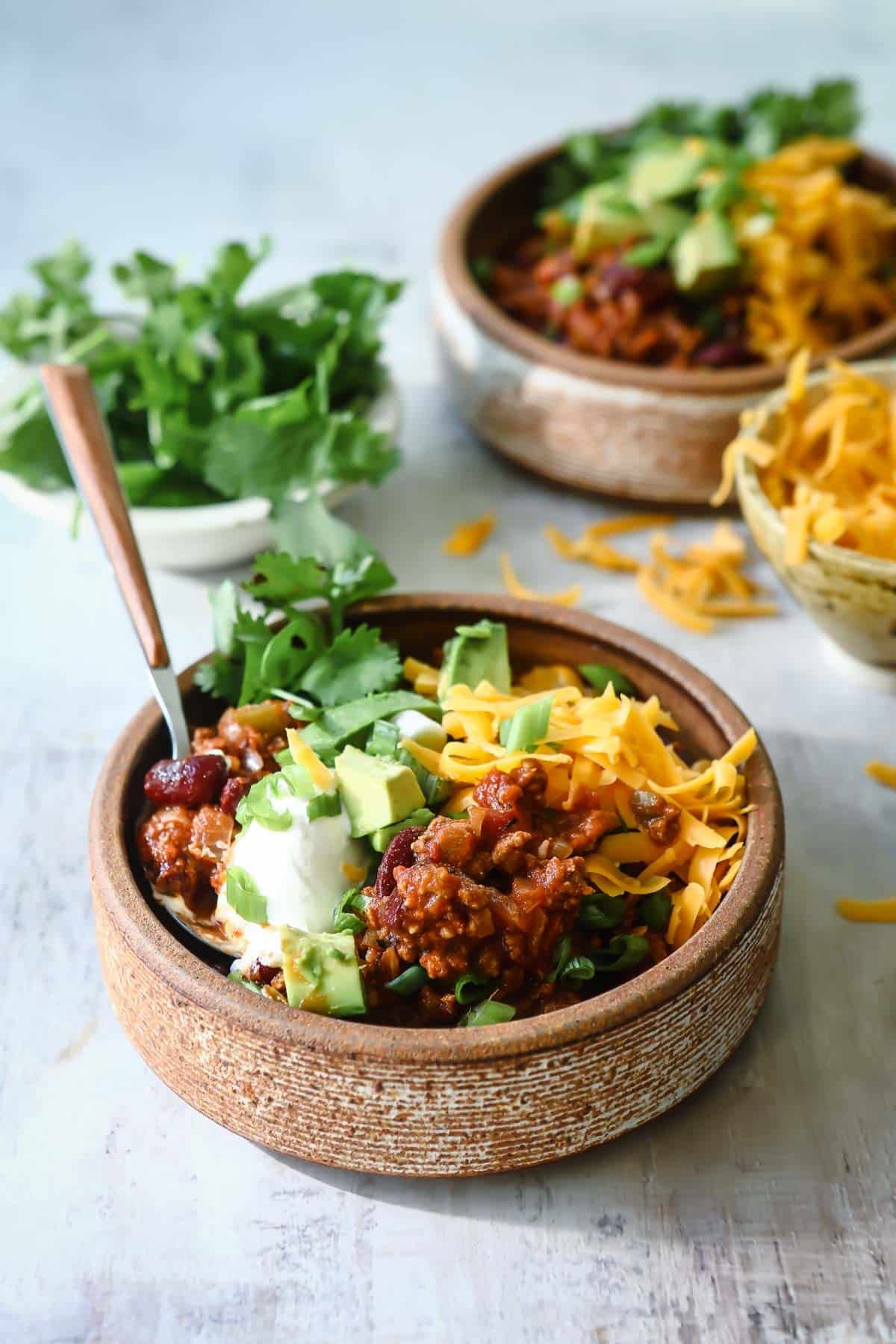 Two bowls of turkey chili with toppings.