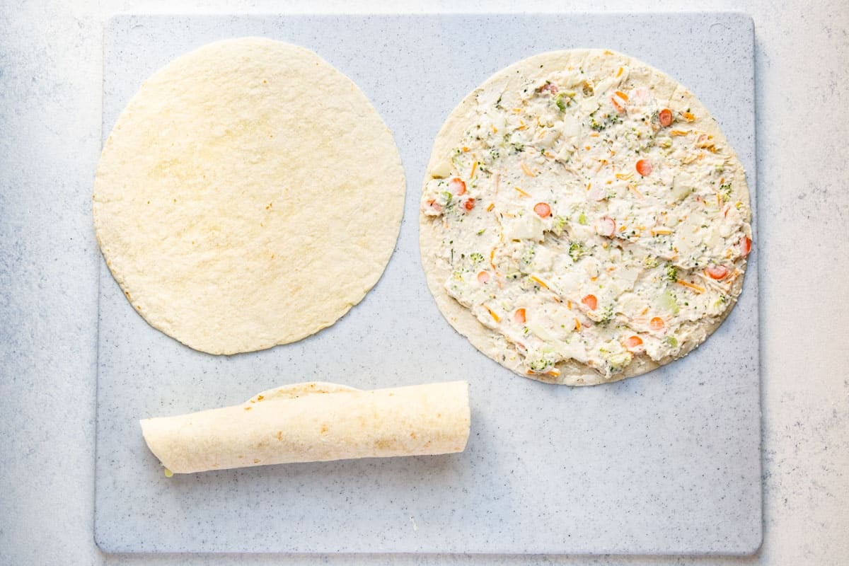 Assembling vegetable tortilla roll ups.