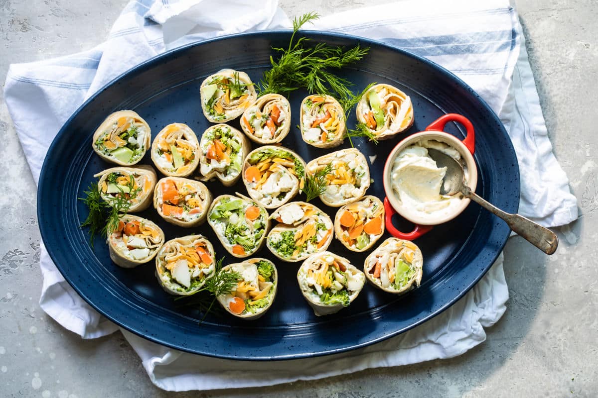 Veggie tortilla roll ups on a blue platter.
